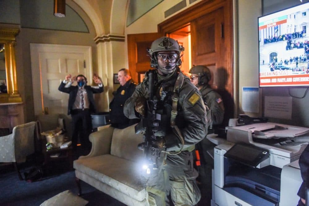 A congressional staffer holds his hands up while the Capitol Police Swat team check everyone in the room as they secure the floor of Trump supporters in Washington, D.C. on January 6, 2021. (Olivier Douliery/AFP via Getty Images)