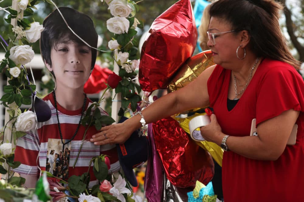 Yvette Reyes of San Antonio puts a rose on the picture of a shooting victim at a memorial outside Robb Elementary School June 1, 2022 in Uvalde, Texas. Nineteen students and two teachers were killed on May 24 after an 18-year-old gunman opened fire inside the school. (Alex Wong/Getty Images)