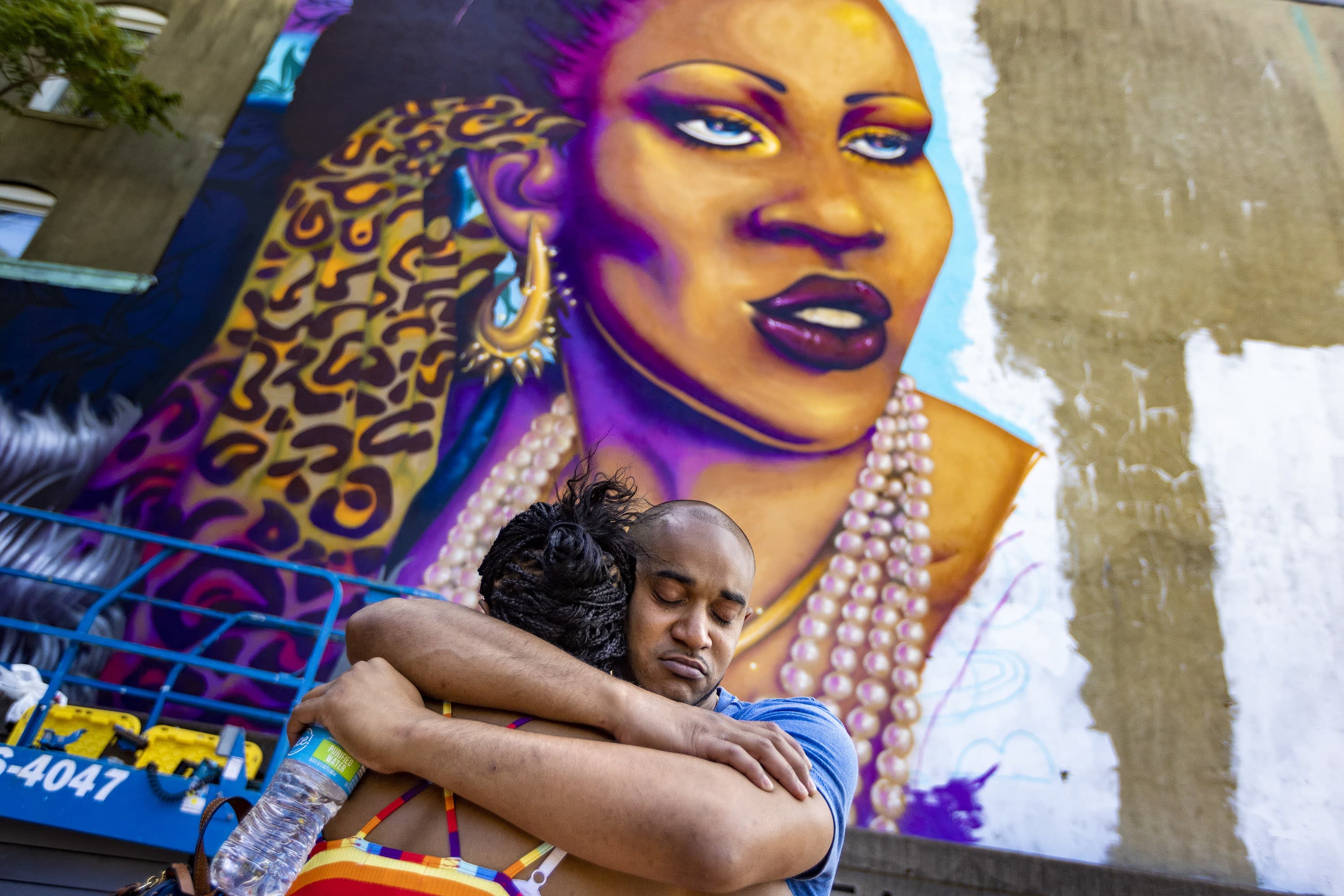 Nephew Taufiq Chowdhury and sister Kim Hester embrace after seeing the almost completed mural of Rita Hester, &quot;Rita's Spotlight,&quot; for the first time by artist Rixy in Allston. (Jesse Costa/WBUR)