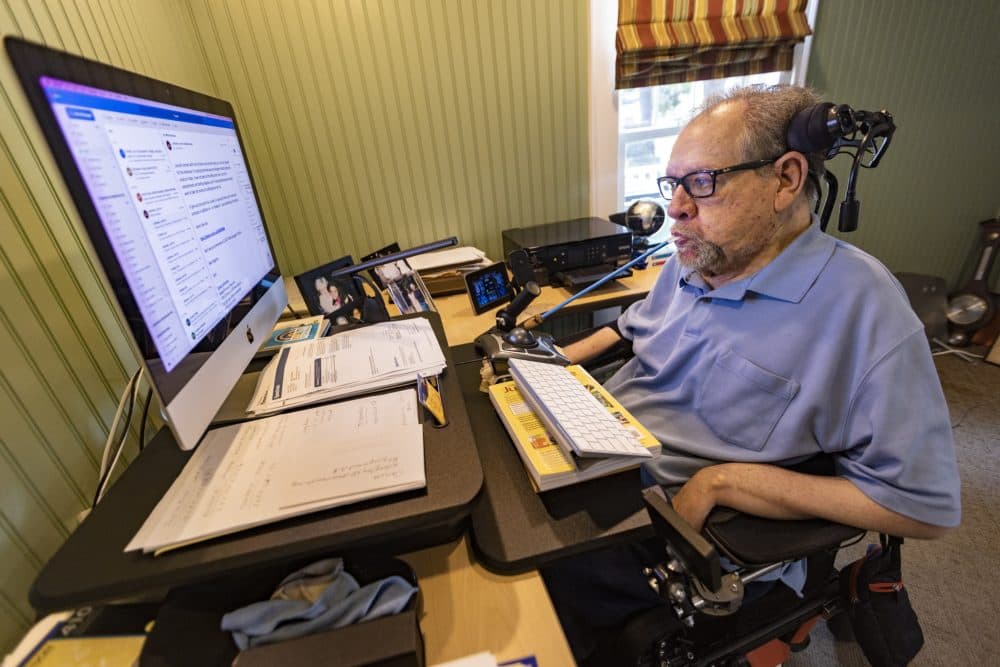 Charlie Carr uses a mouth wand to direct a trackball to control his computer. (Jesse Costa/WBUR)