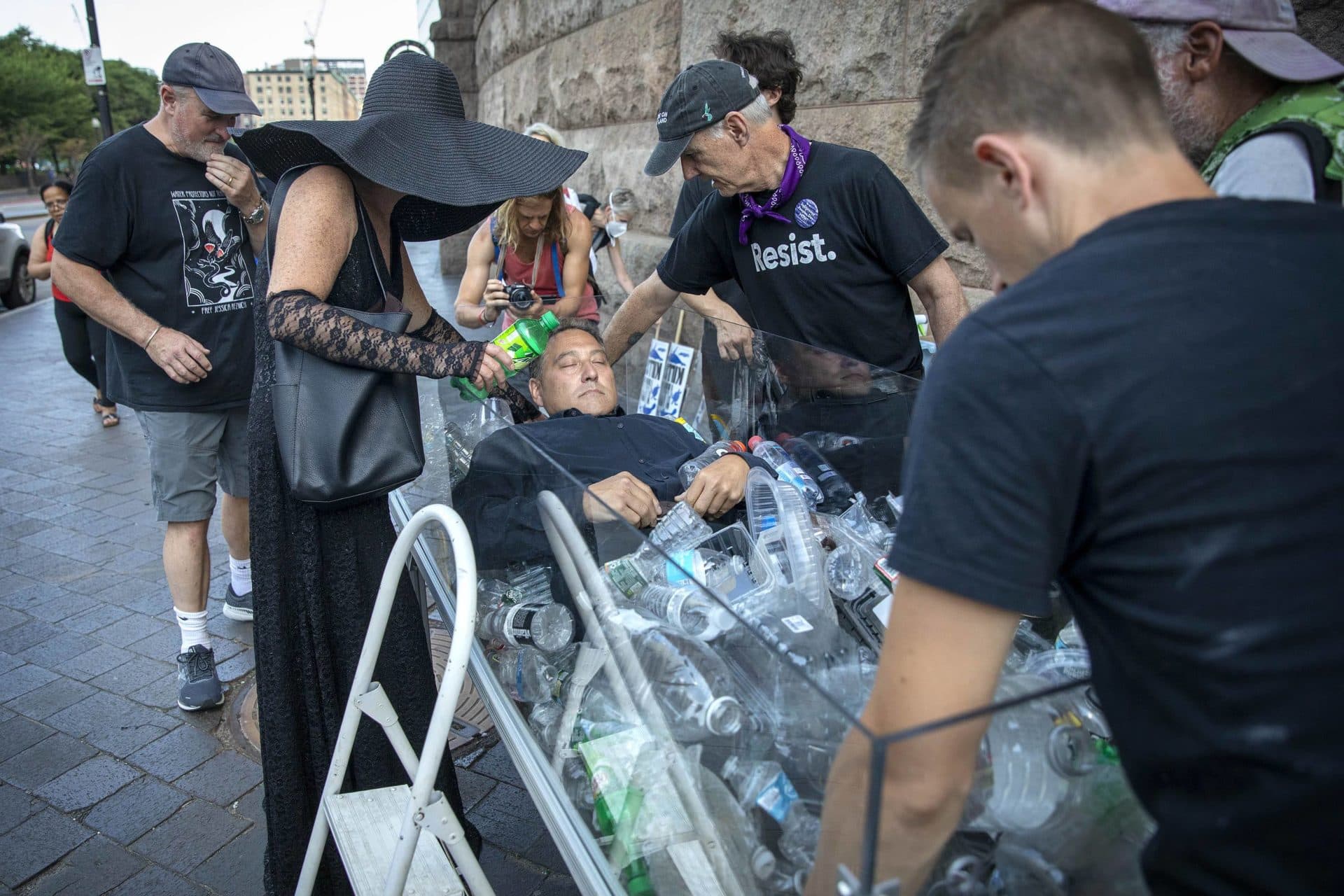 Artist Anne-Katrin Spiess' team lowers JD Cohen into the coffin as they prepare for a performance of &quot;Death by Plastic&quot; in front of South Station. (Robin Lubbock/WBUR)