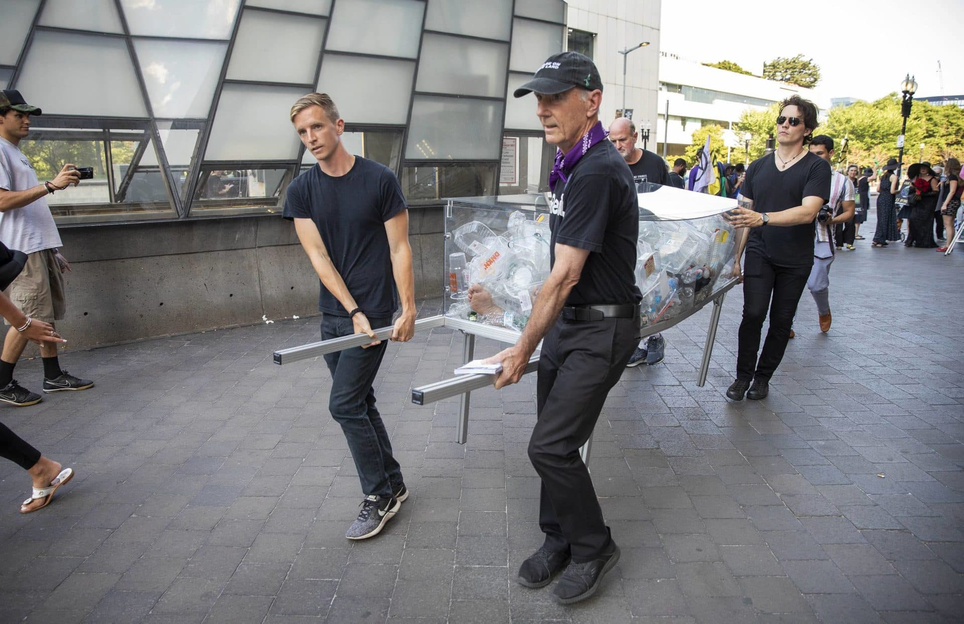 Artist Anne-Katrin Spiess' team walk the &quot;Death by Plastic&quot; coffin to the entrance of South Station. (Robin Lubbock/WBUR)