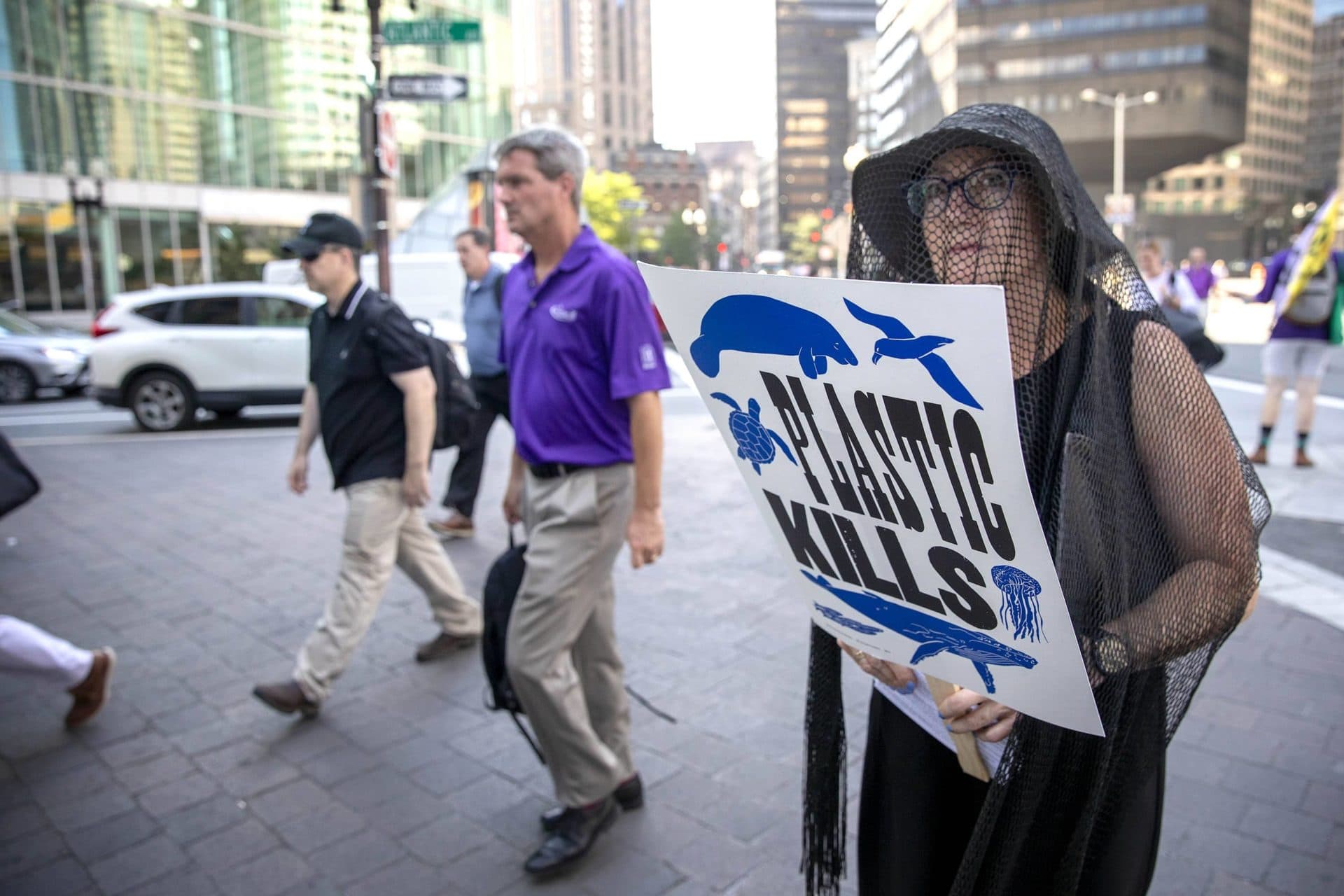 Commuters walk past mourner Sarah Jordan at at a performance of &quot;Death by Plastic&quot; in front of South Station. (Robin Lubbock/WBUR)