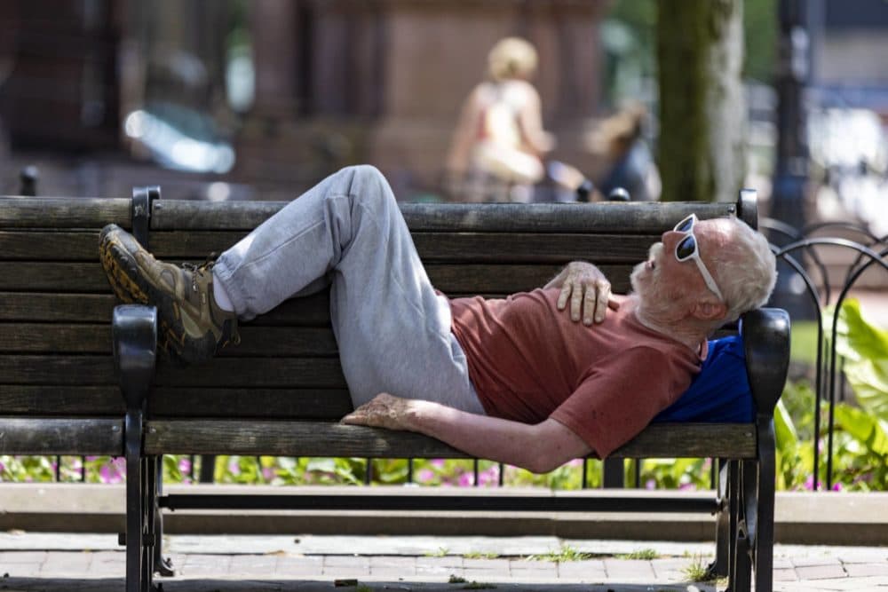 A man rests on a bench in the shade in Copley Square. (Jesse Costa/WBUR)