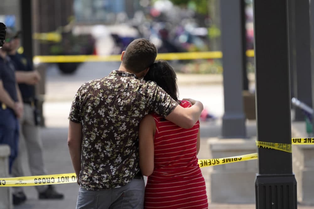 Brooke and Matt Strauss, who were married Sunday, look toward the scene of the mass shooting in downtown Highland Park, Ill., a Chicago suburb, after leaving their wedding bouquets near the scene of Monday's mass shooting, Tuesday, July 5, 2022. (Charles Rex Arbogast/AP)