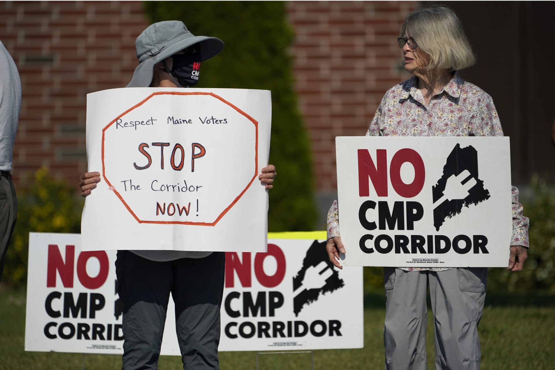 Protesters hold signs outside the Augusta Civic Center where a state meeting on Central Maine Power's proposed hydropower corridor is taking place, July 20, 2022, in Augusta, Maine. Voters rejected the corridor in November. (Robert F. Bukaty/AP)