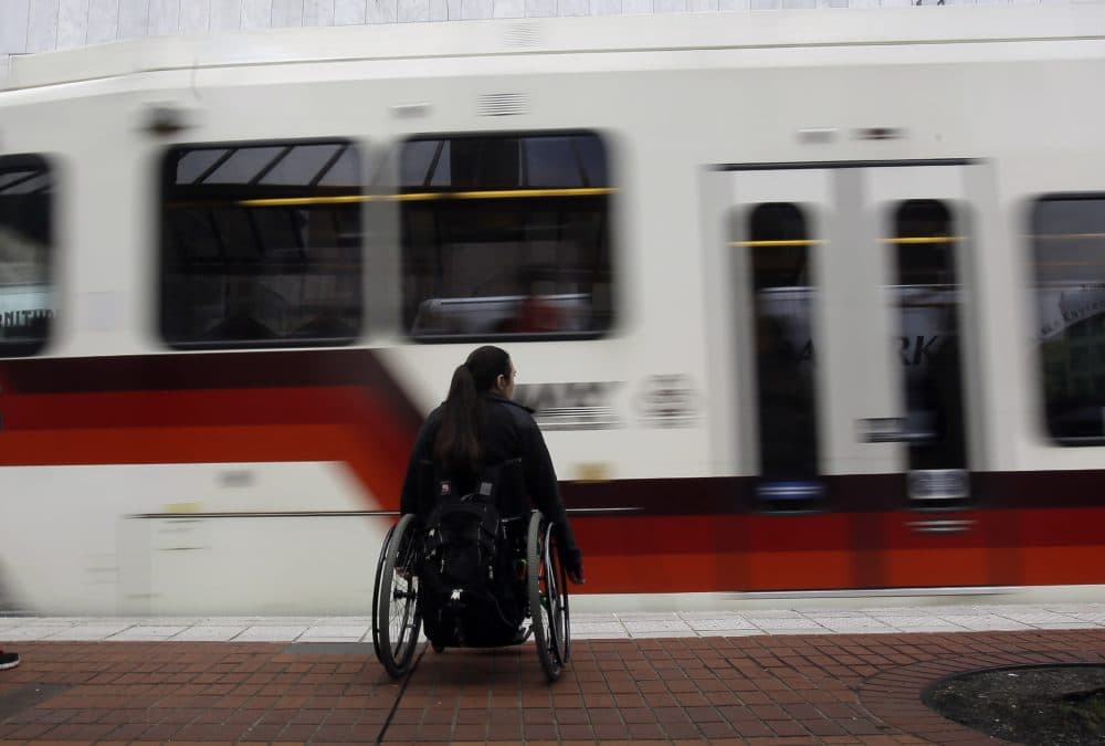 A rider waits to board an incoming MAX train in Portland, Ore. (Don Ryan/AP)