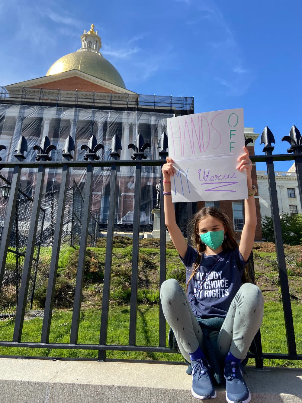 The author's daughter holding a protest sign at the State House, Boston, Mass. (Courtesy Anri Wheeler)