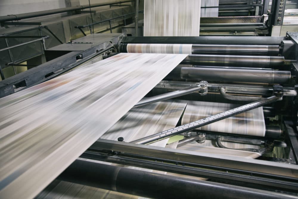 Newspapers being printed in printing press.