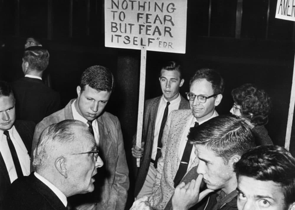 Students carrying signs against the John Birch Society listen as an older man defends the society founded by Robert Welch before Welch spoke at an anti-communist meeting. (Photo by Bettmann Archive/Getty Images)