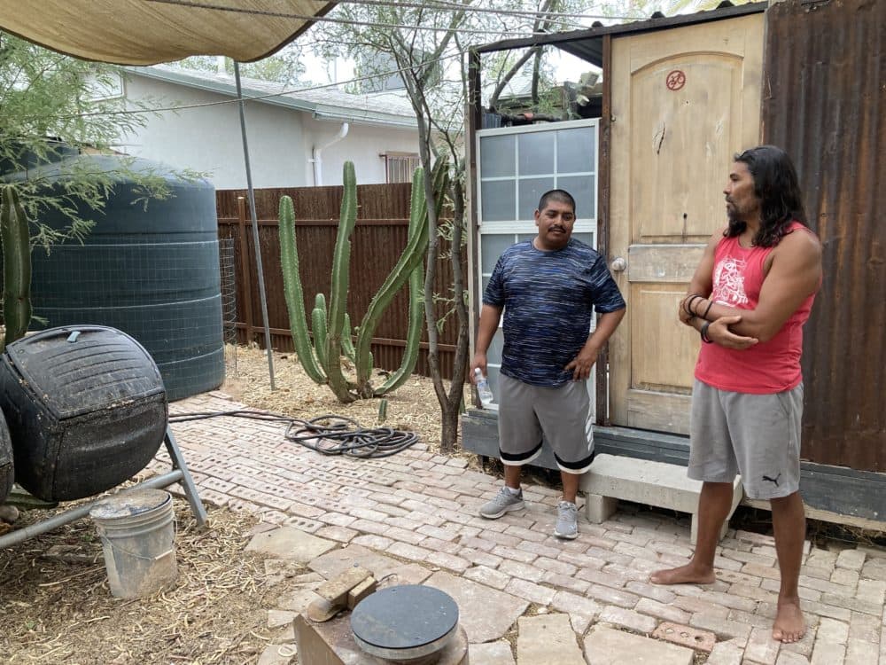 Evaristo Barajas, right, in his backyard. The tank holds 1,000 gallons of rain. (Peter O'Dowd/ Here &amp; Now)
