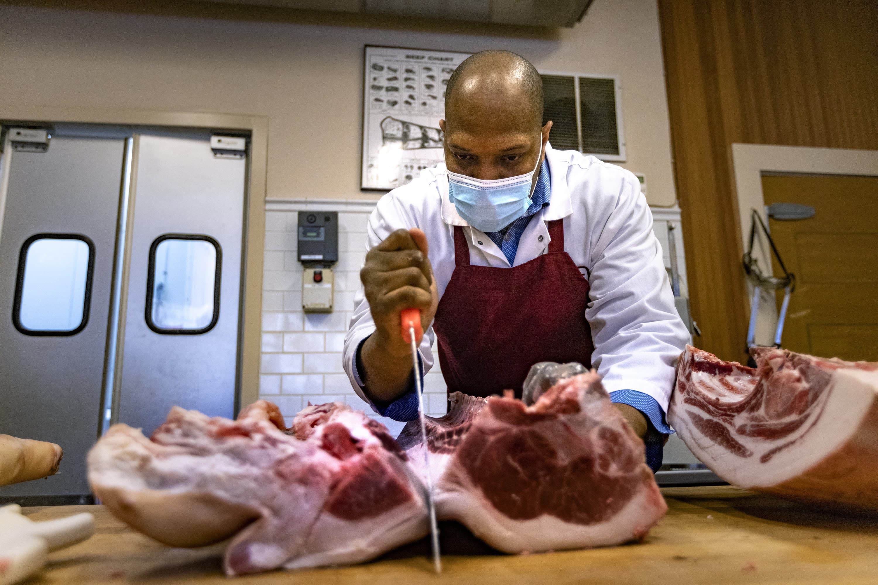 Christopher Walker slices pig ribs before cutting pork chops. (Jesse Costa/WBUR)