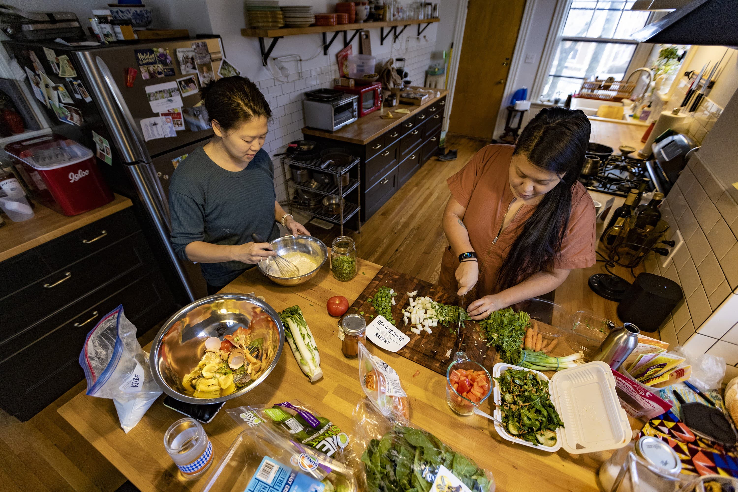 Mei Li prepares batter while Irene Li chops vegetables to make okonomiyaki, a Japanese pancake. (Jesse Costa/WBUR)