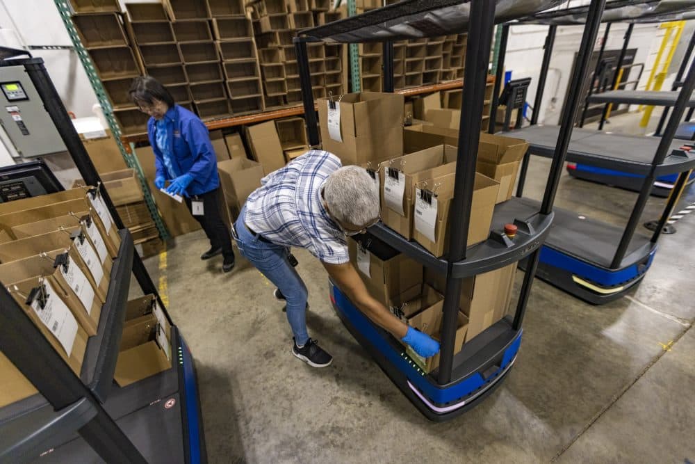 Top Notch Distributors associates Lynda Nguyen and Maria Pinto set up a “Chuck” with empty boxes for another associate to fulfill a customer order. (Jesse Costa/WBUR)