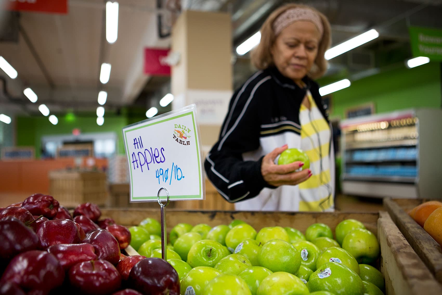 A woman looks at an apple at Daily Table in Dorchester. (Jesse Costa/WBUR)