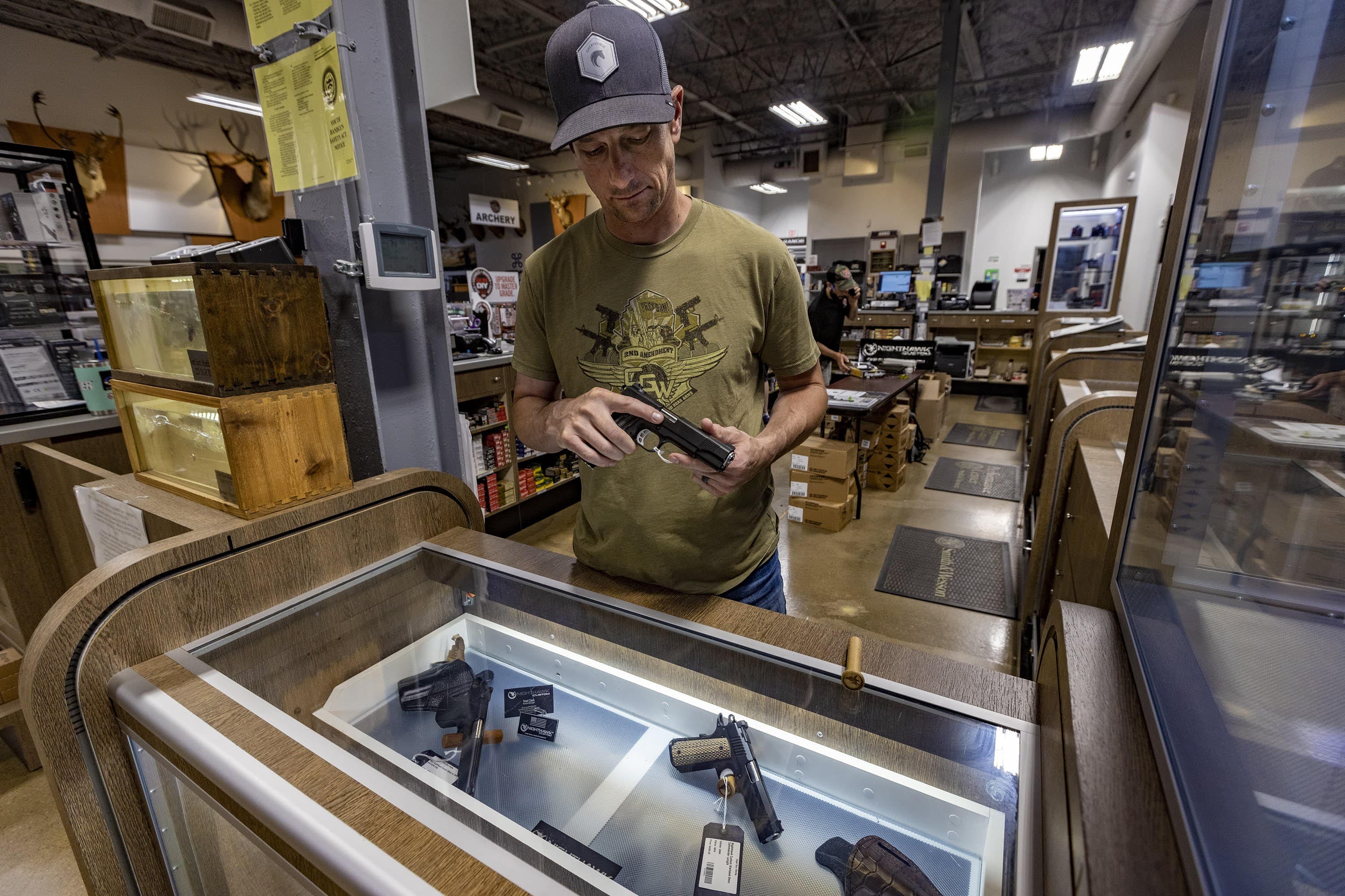 Toby Leary shows a handgun from the showroom cabinet at Cape Gun Works in Hyannis. (Jesse Costa/WBUR)
