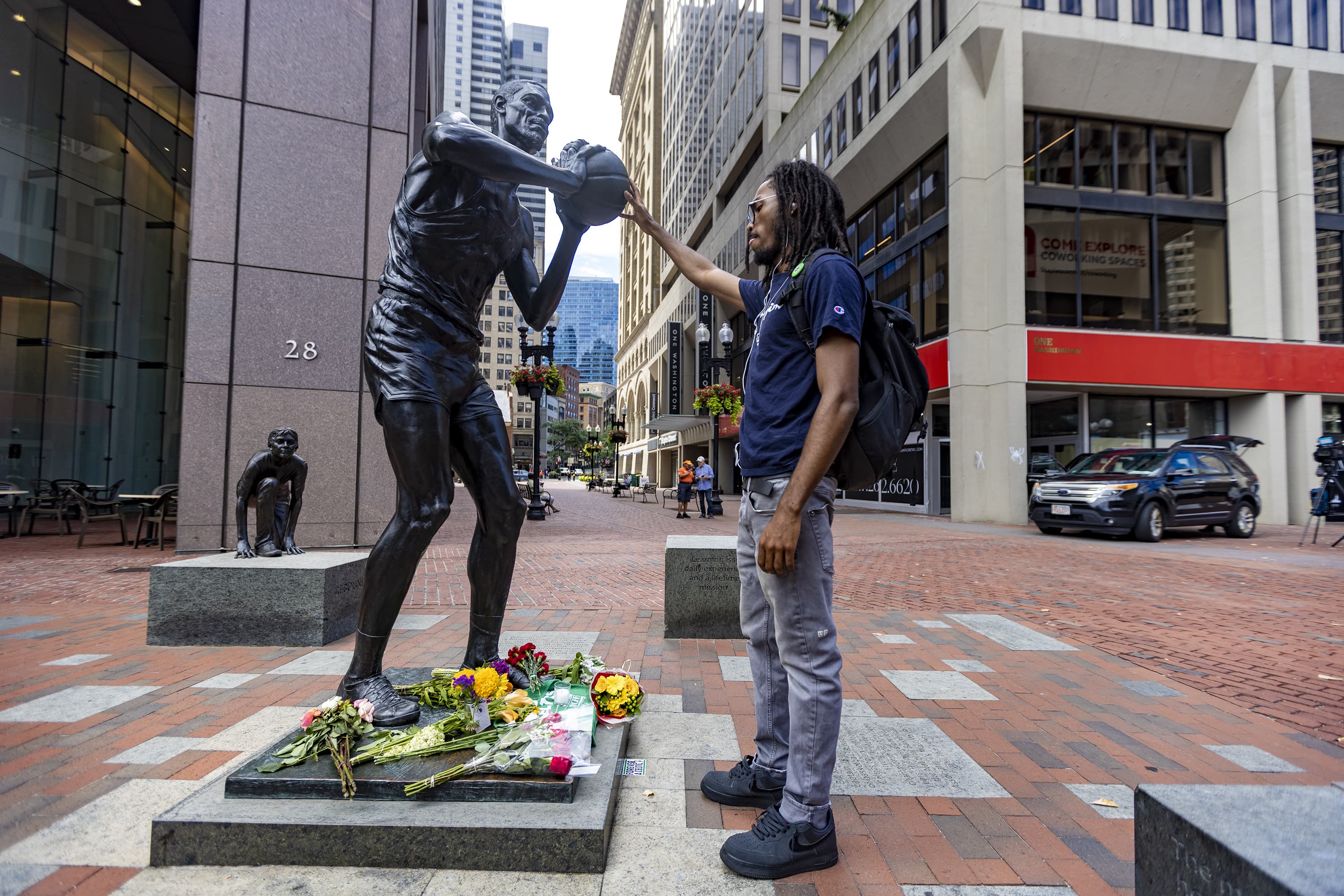 Neil Lamber touches the ball on the Bill Russell statue at City Hall Plaza in Boston. (Jesse Costa/WBUR)