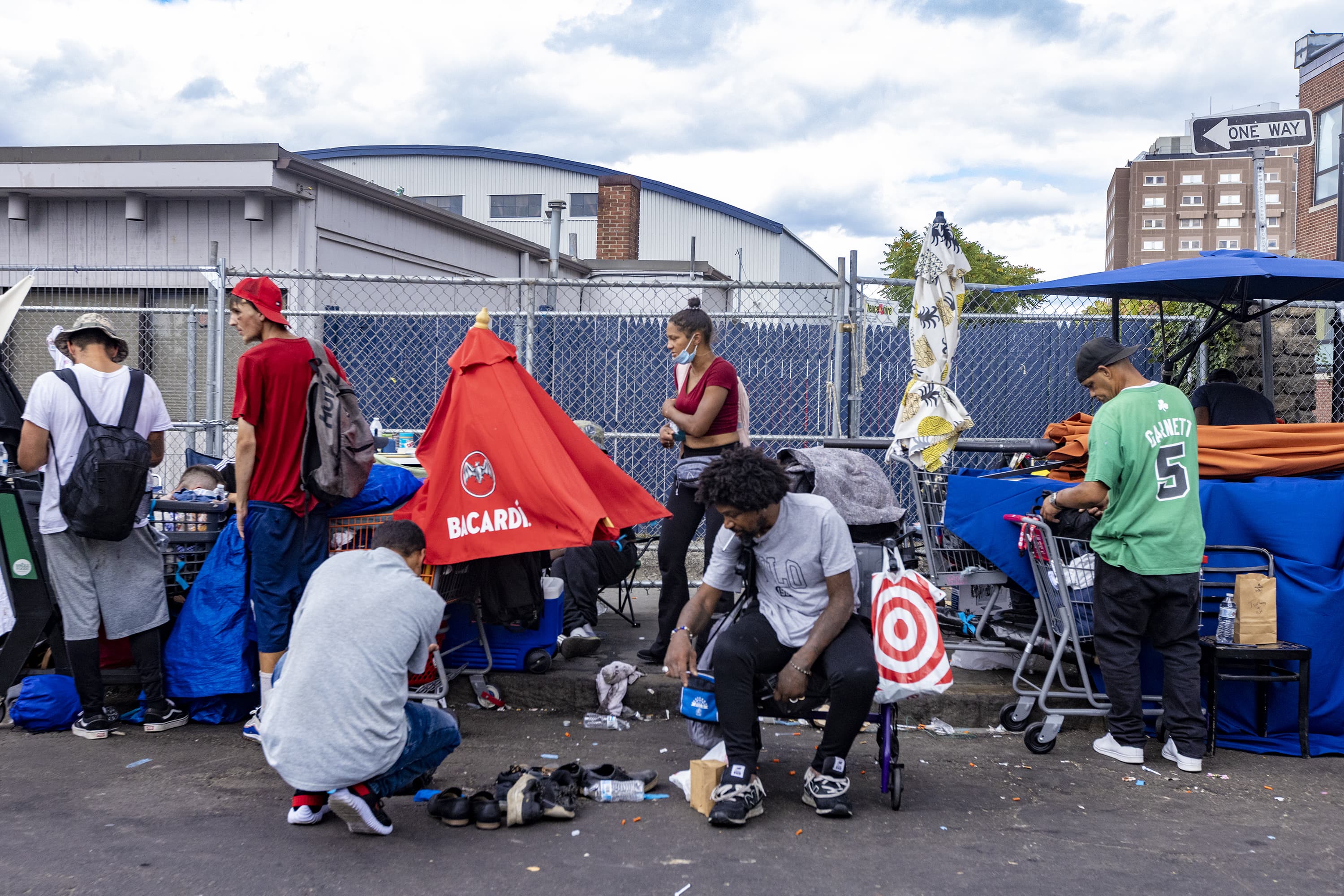 People sit on Southampton Street in the Mass. and Cass area of Boston last week. (Jesse Costa/WBUR)