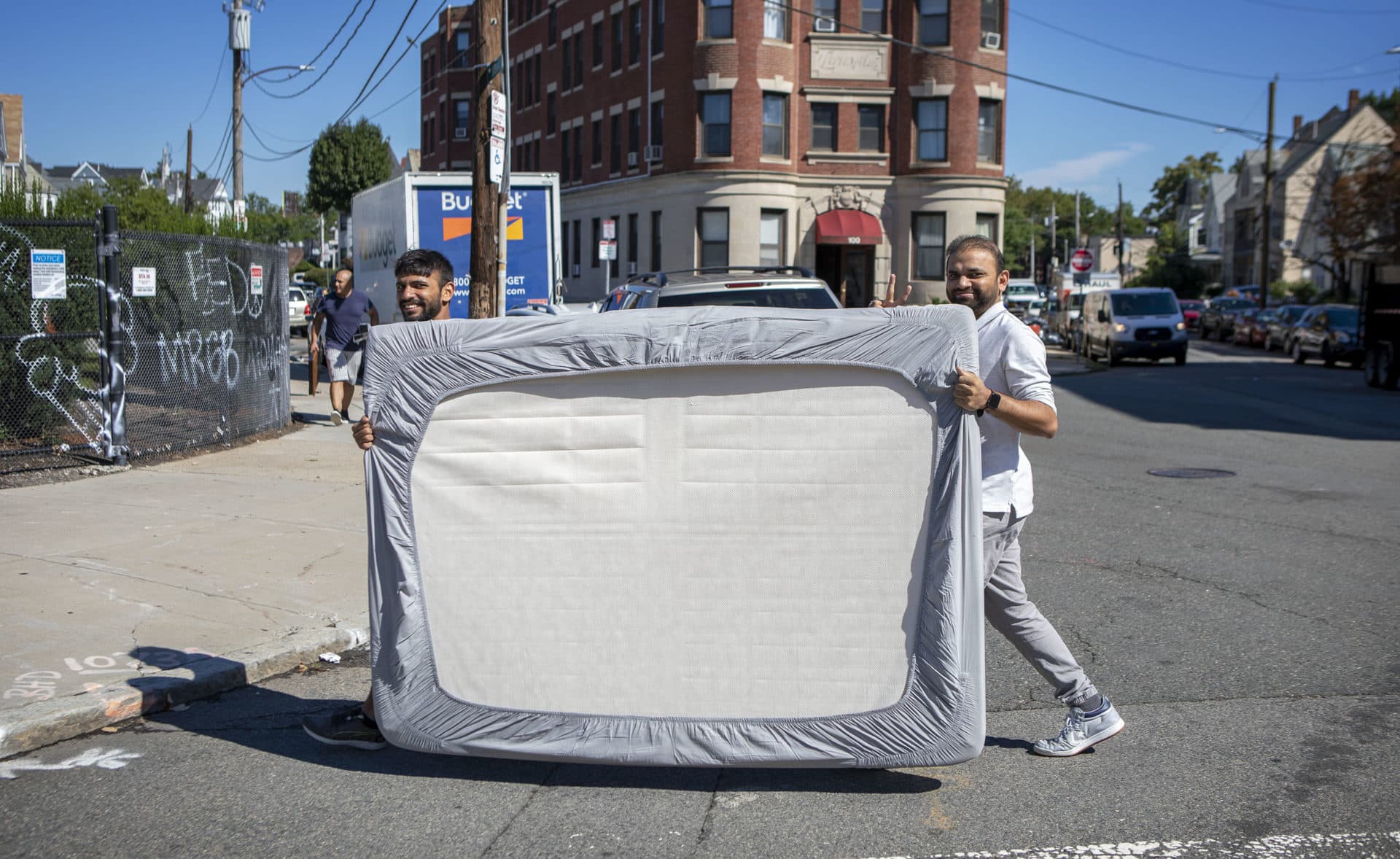 Two men walk a mattress along Commonwealth Ave. on move out day. (Robin Lubbock/WBUR)
