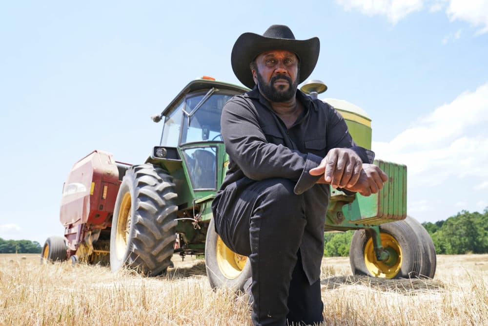Farmer John Boyd Jr., poses in front of his hay bailer at his farm in Boydton, Va., Thursday, May 27, 2021. (Steve Helber/AP)