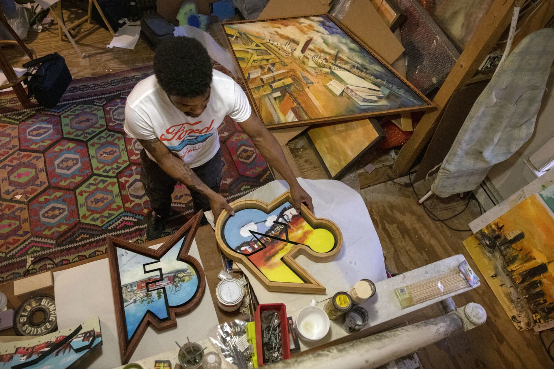 Artist Nygel Jones looks through some of his paintings in his studio. (Robin Lubbock/WBUR)