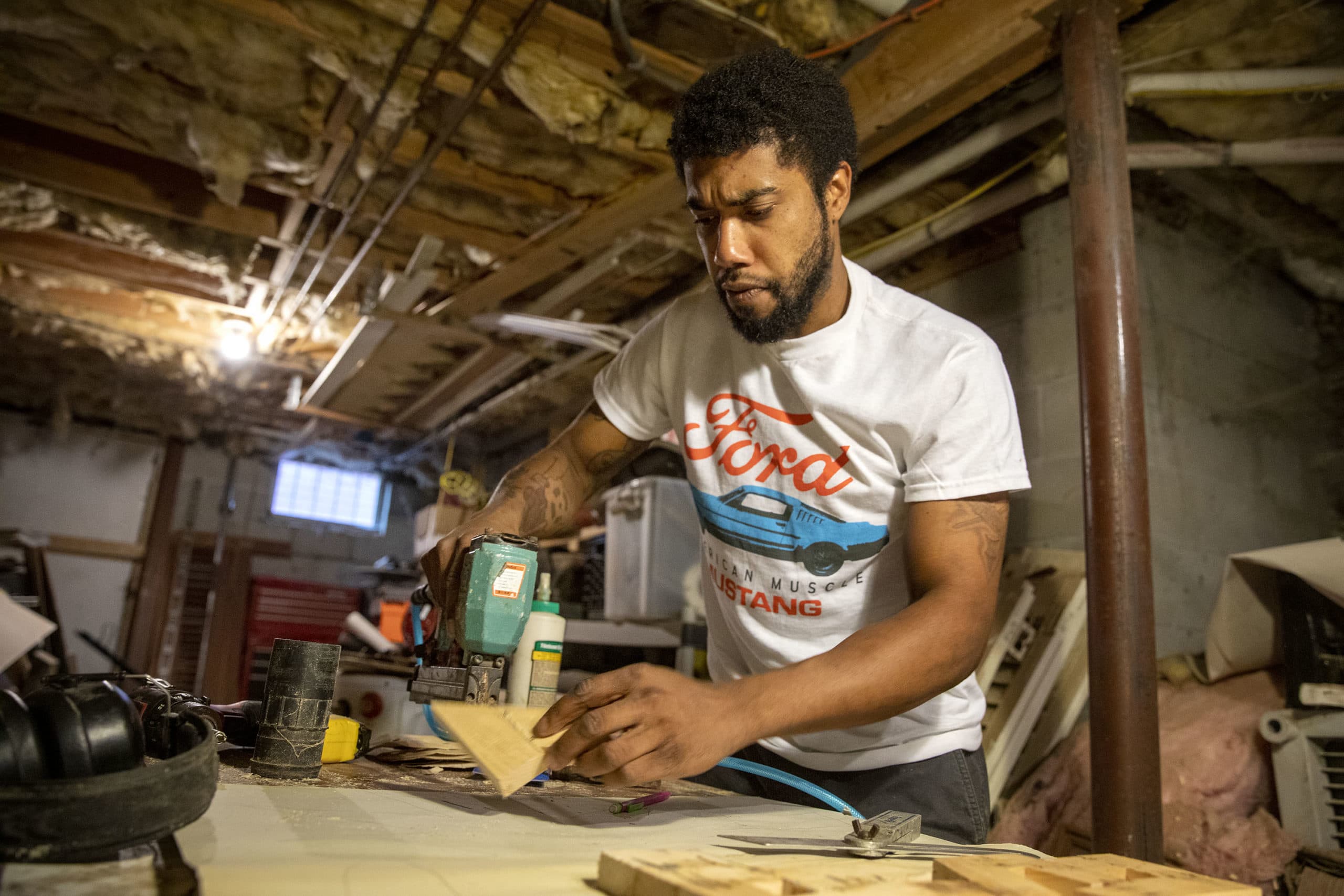 Artist Nygel Jones pins a frame together in his workshop. (Robin Lubbock/WBUR)