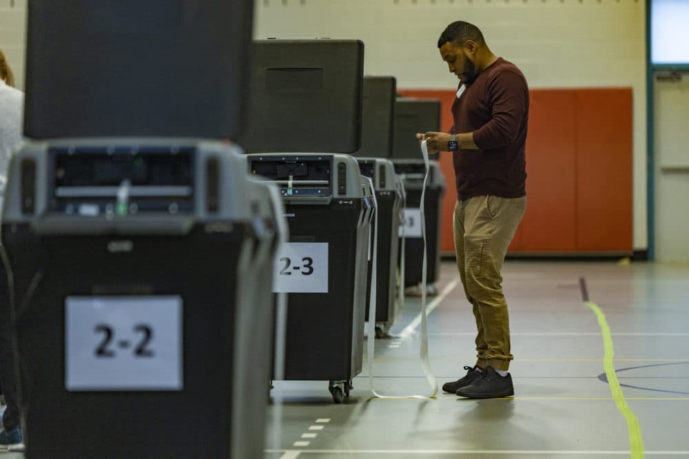A poll worker prepares one of the ballot machines shortly before the polls open at the Williams Junior High School Auditorium in Chelsea on Primary Election Day. (Jesse Costa/WBUR)