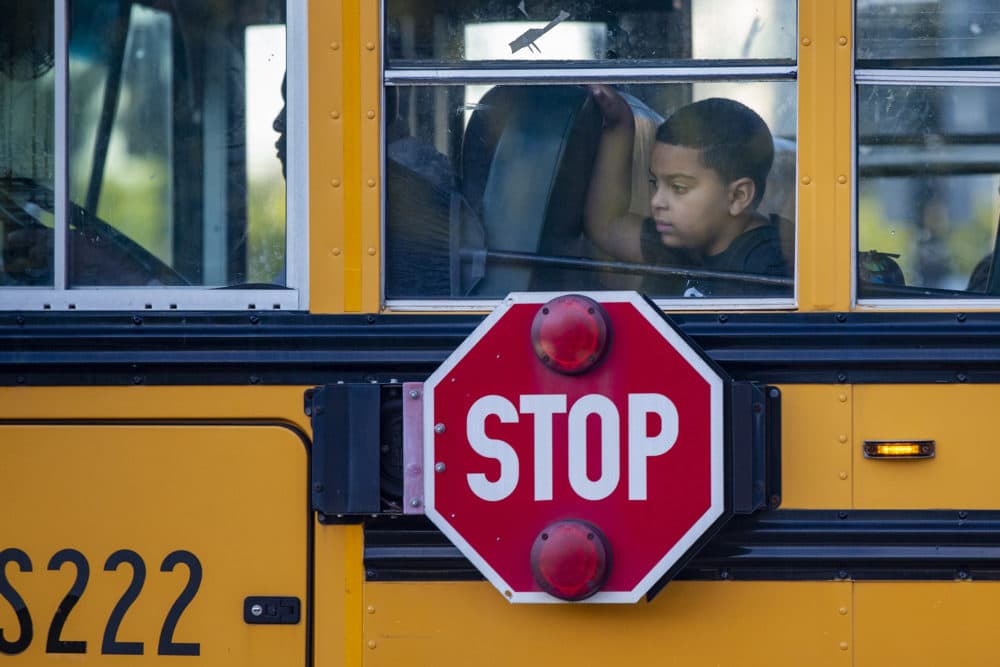 A young boy looks out the window of a Boston Public Schools bus traveling down Dorchester Avenue on the first day of school in Boston. (Jesse Costa/WBUR)