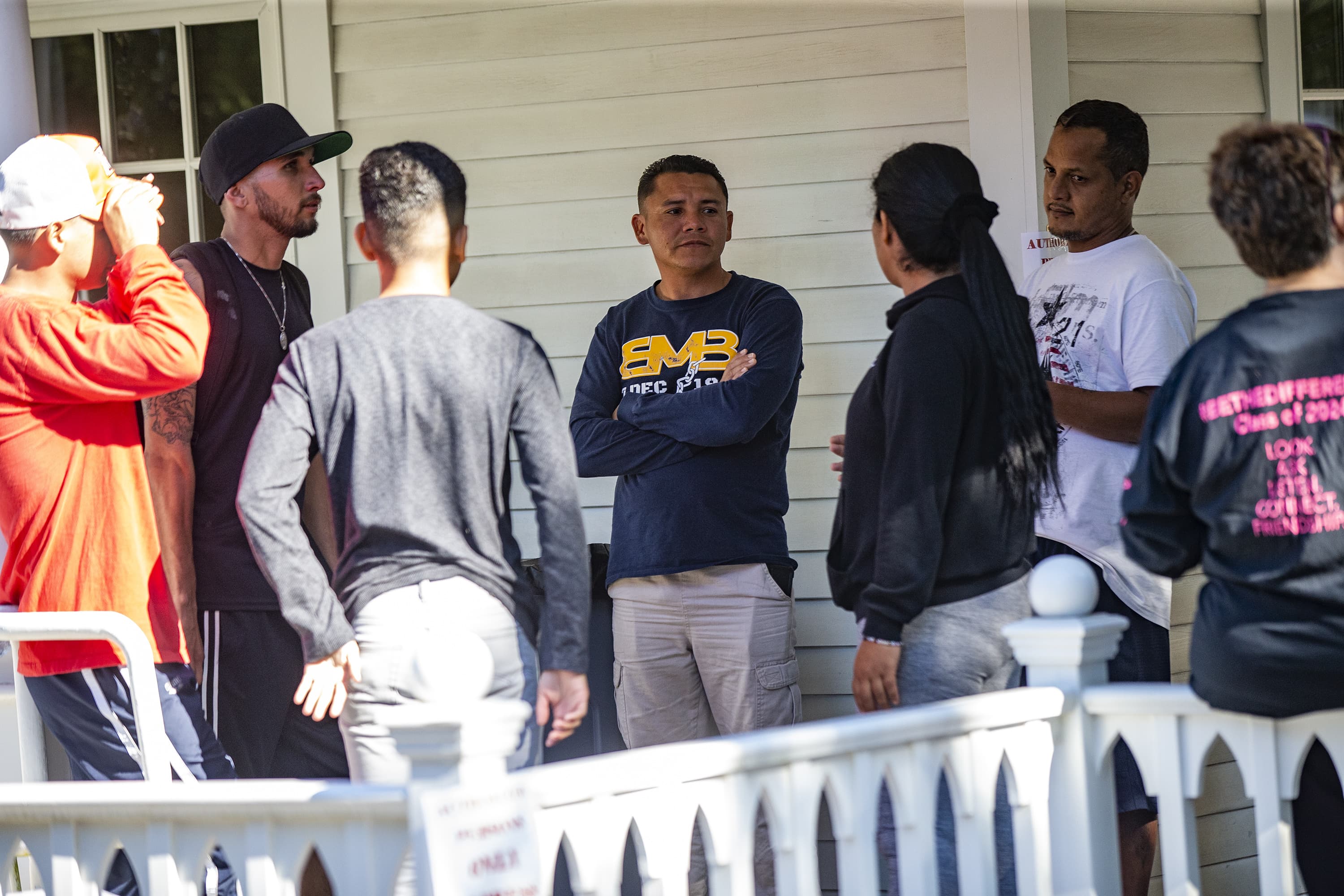 Migrants from Venezuela, sent to Martha’s Vineyard by way of Texas and Florida, stand and talk to one another at St. Andrew’s Parish House in Edgartown. (Jesse Costa/WBUR)
