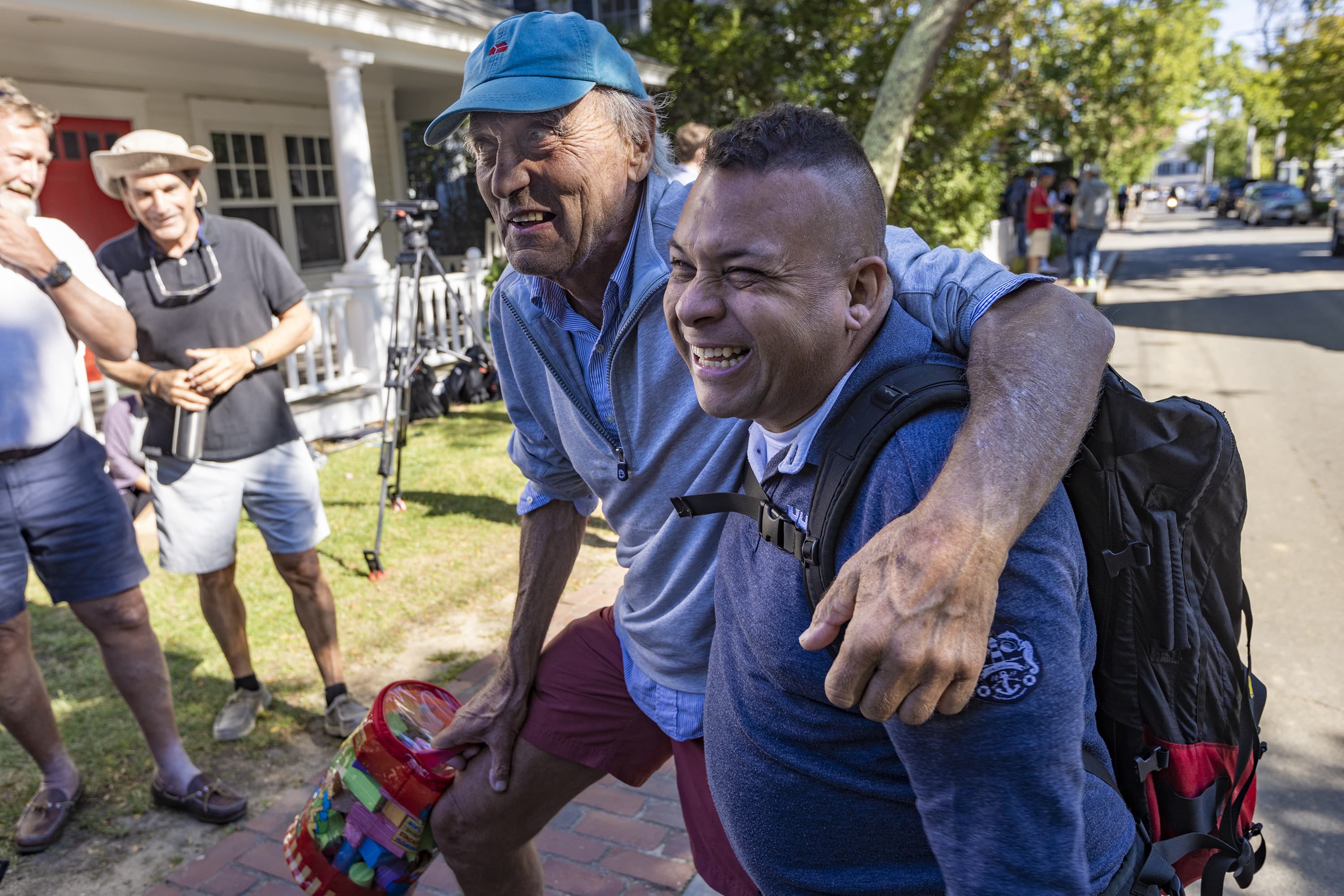 Longtime Martha’s Vineyard resident Jeff Whipple embraces one of the migrants from Venezuela outside of St. Andrew’s Parish House in Edgartown. (Jesse Costa/WBUR)