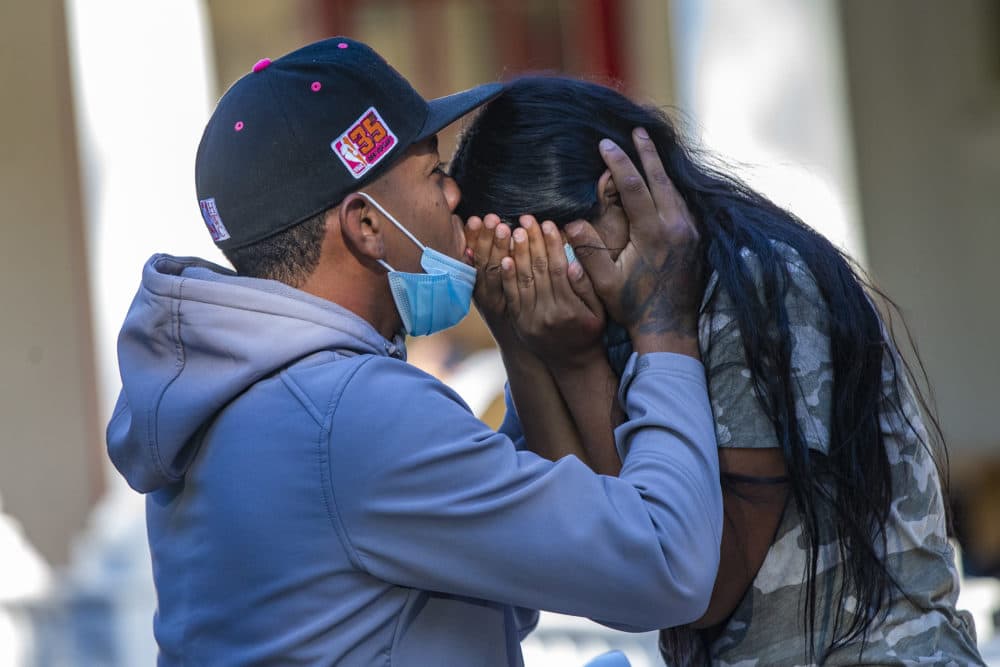 A migrant young couple embraces on the porch of St. Andrew’s Parish House in Edgartown. (Jesse Costa/WBUR)