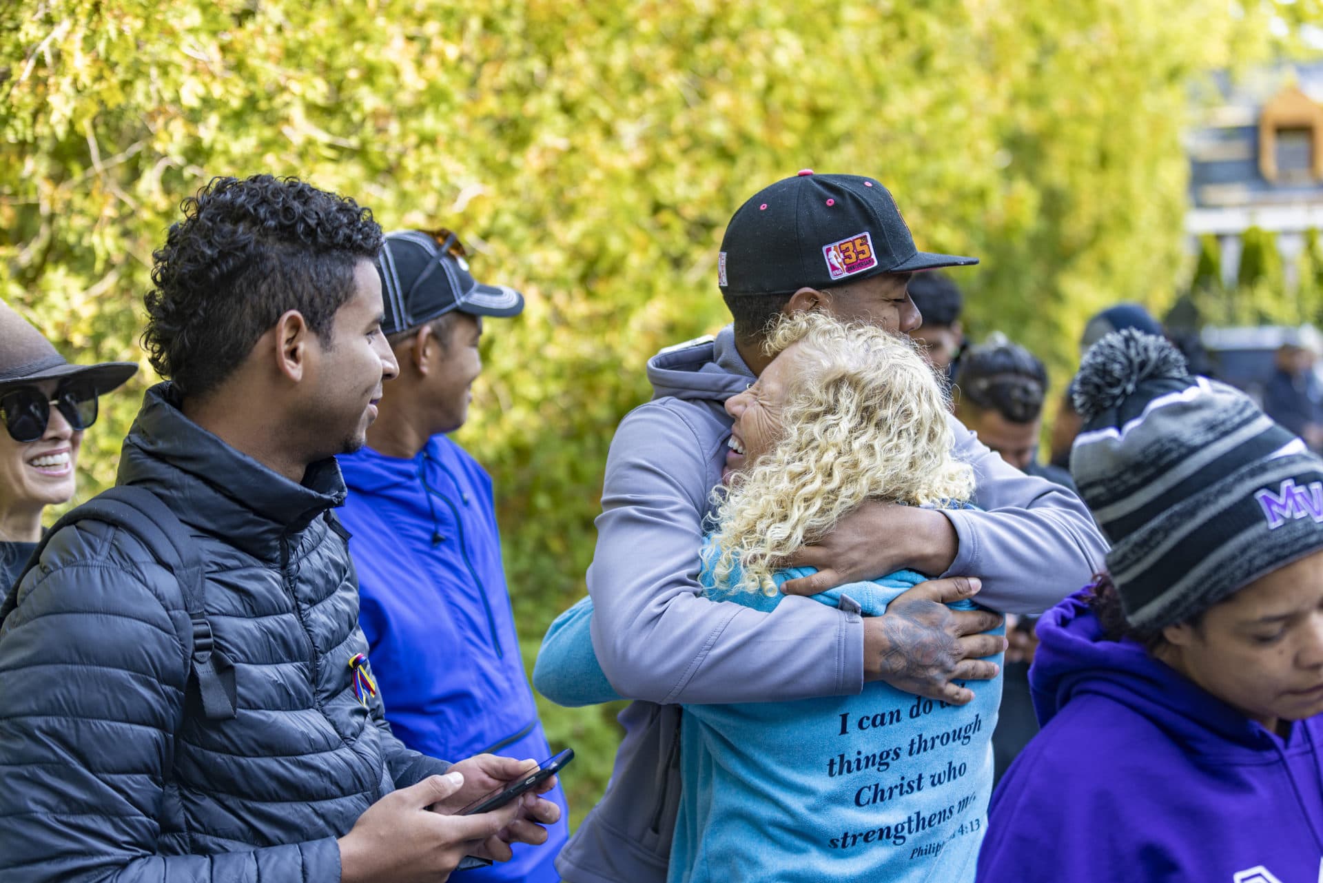 Lisa Belcastro says goodbye to the group of Venezuelan immigrants as they leave St. Andrews Parish House for Joint Base Cape Cod. (Jesse Costa/WBUR)