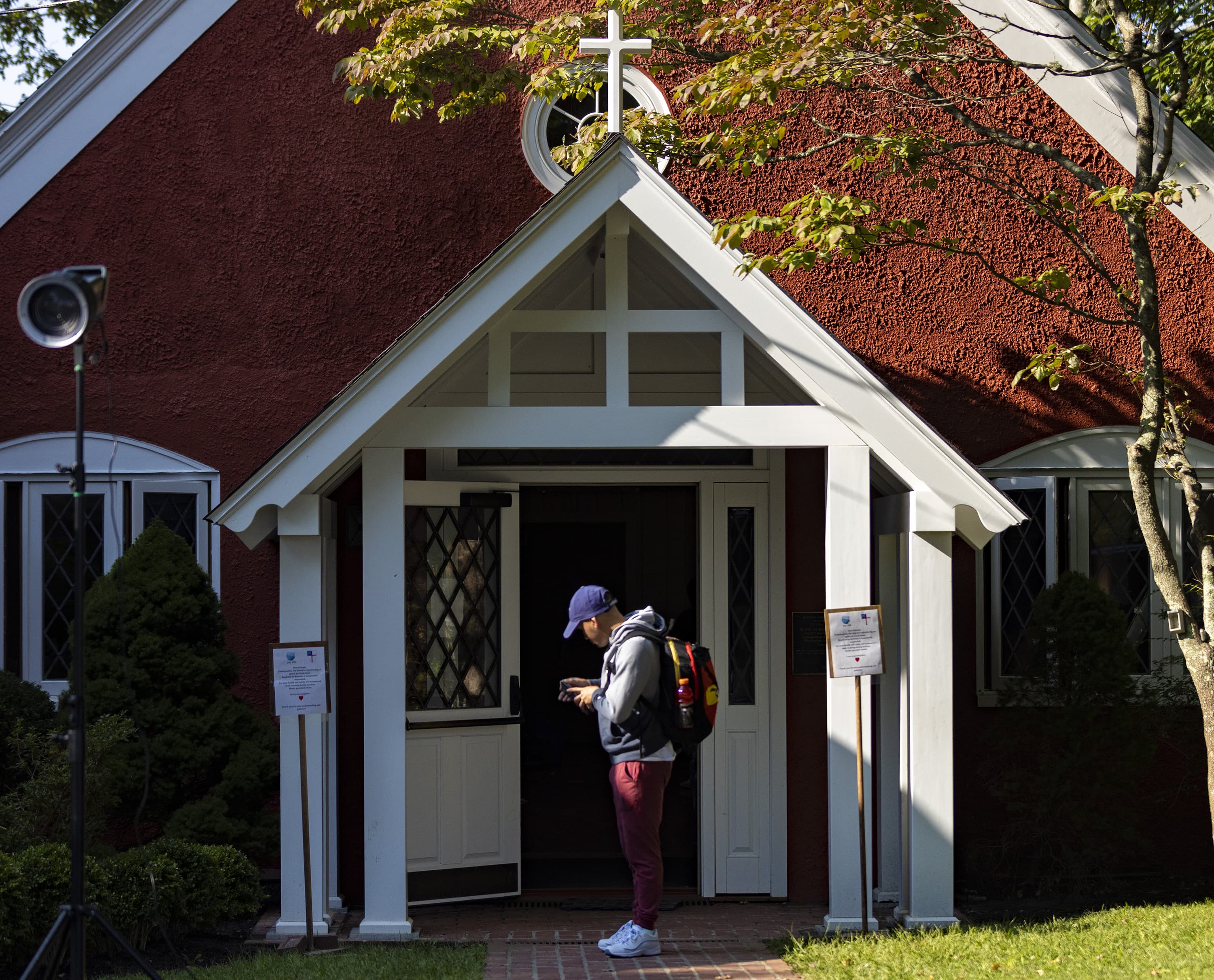 A Venezuelan immigrant looks at his phone outside of the St. Andrews Church before boarding buses to leave Edgartown. (Jesse Costa/WBUR)