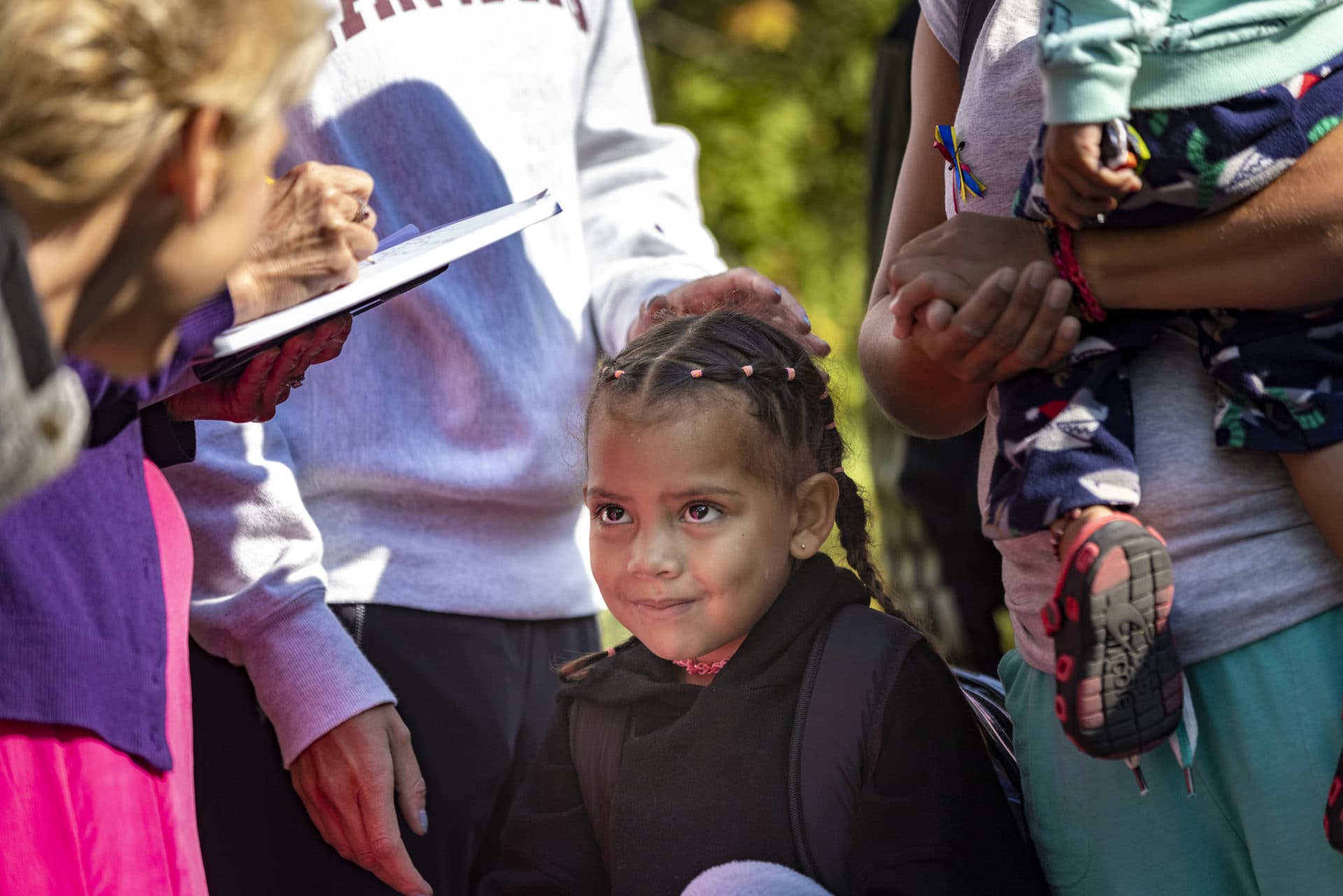 A young Venezuelan girl smiles as a volunteer says goodbye before boarding a bus to leave Edgartown and take them to the mainland. (Jesse Costa/WBUR)