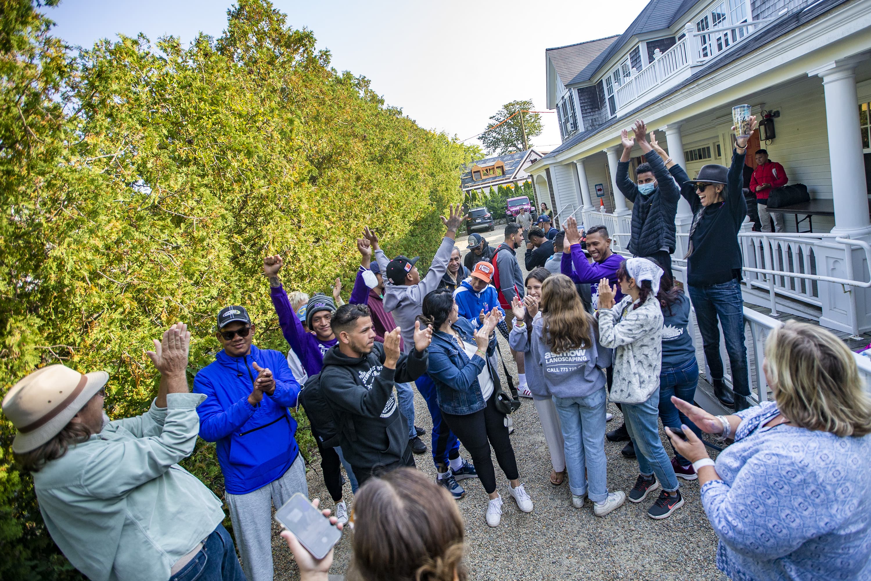 Volunteers and immigrants cheer in the driveway of St. Andrews Parish House on Martha's Vineyard. (Jesse Costa/WBUR)