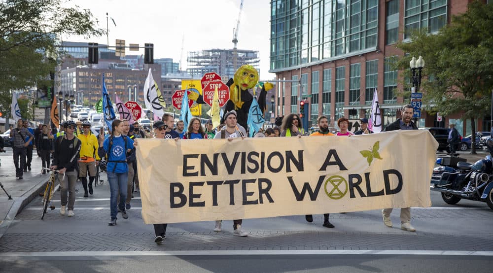 Extinction Rebellion protesters walk along Seaport Boulevard. (Robin Lubbock/WBUR)