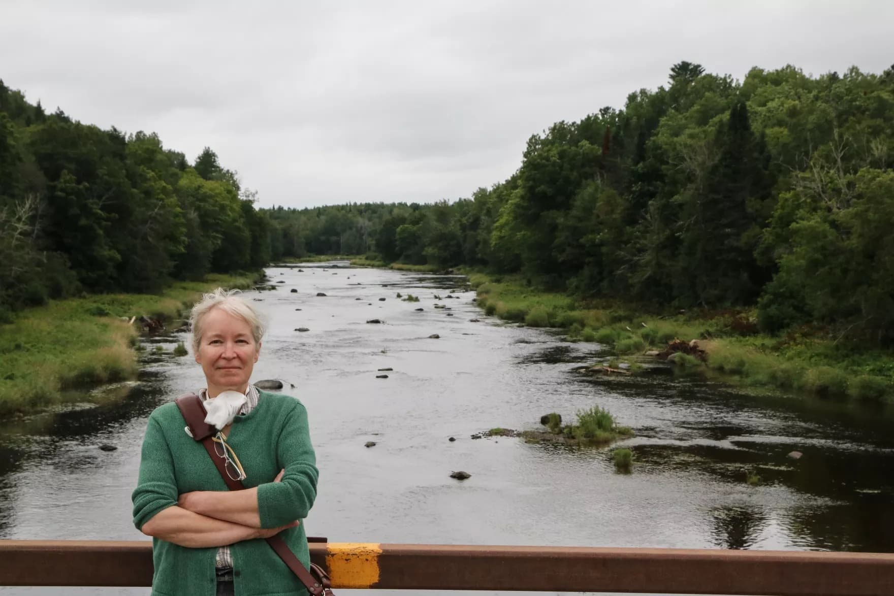 Sharri Venno, environmental planner for the Houlton Band of Maliseet Indians, stands in front of a section of Meduxnekeag River that's been restored to a more natural state that better suits salmon and other native species. (Murray Carpenter/Maine Public)