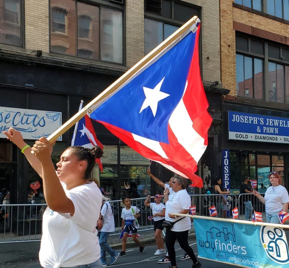 A woman holds a Puerto Rican flag during the Springfield Puerto Rican Parade on Sept. 18, 2022. (Elizabeth Román/New England Public Media)