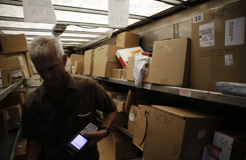 Boxes sit on the truck as UPS driver Marty Thompson registers a delivery. (David Goldman/AP)