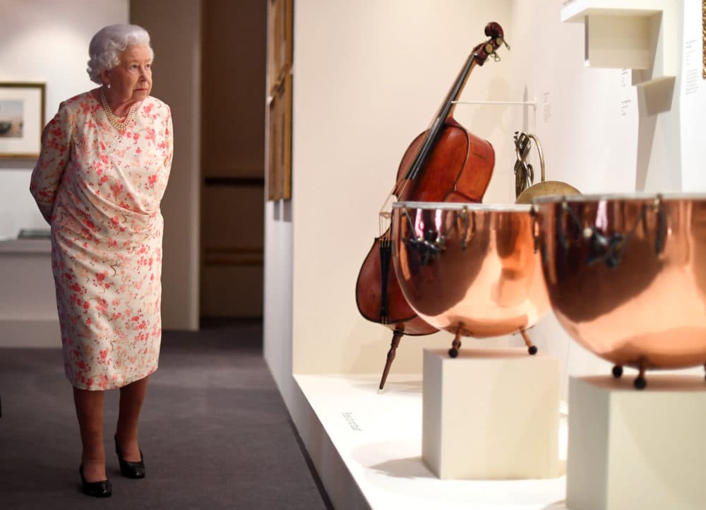 Britain's Queen Elizabeth II looks at musical instruments used by Queen Victoria's private orchestra, as part of an exhibition to mark the 200th anniversary of the birth of Queen Victoria, for the Summer Opening of Buckingham Palace in London on July 17, 2019. (Victoria Jones/POOL/AFP via Getty Images)