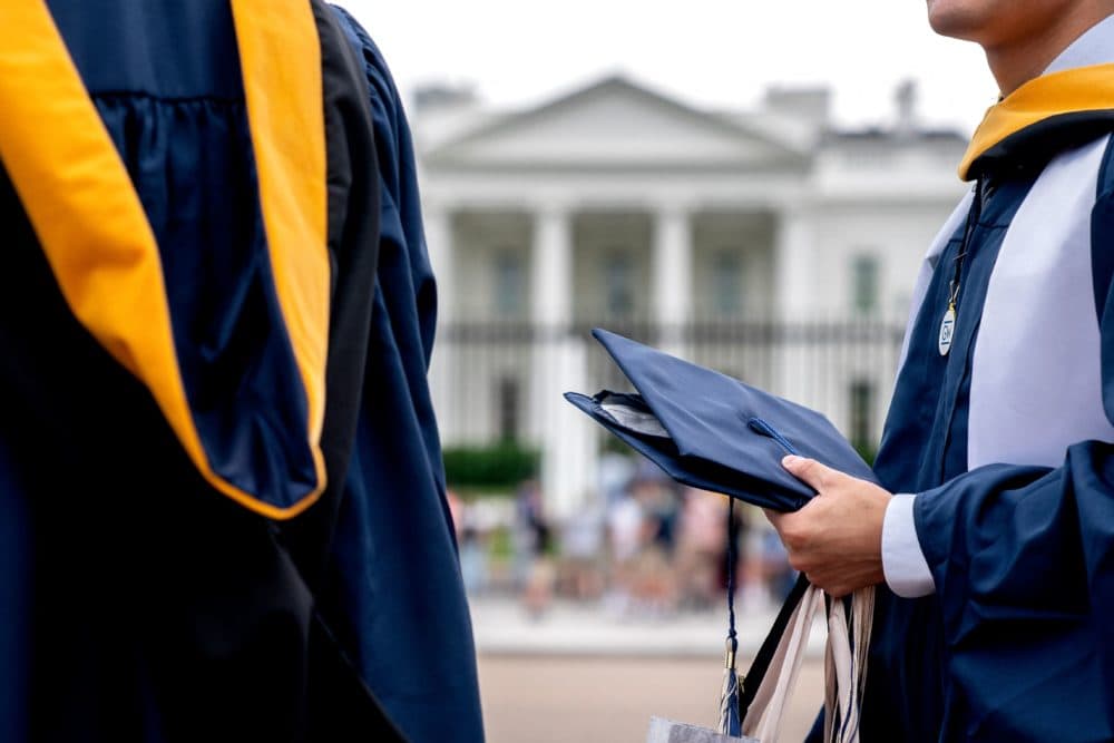 Students from George Washington University wear their graduation gowns outside of the White House on May 18, 2022 to push for student loan forgiveness. (Stefani Reynolds/AFP via Getty Images)