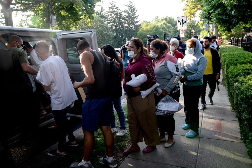 Migrants from Venezuela, who boarded a bus in Texas, wait to be transported to a local church by volunteers after being dropped off outside the residence of Vice President Kamala Harris. (Stefani Reynolds/AFP via Getty Images)