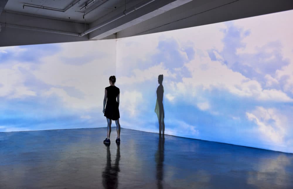 A person looks at an image of the sky projected onto the walls of a gallery. (Getty Images)