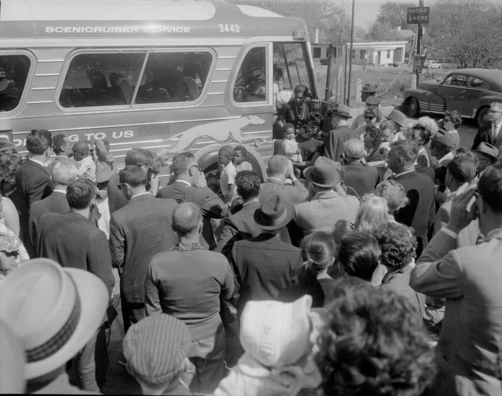 Black families boarding a bus heading north with a crush of reporters and photographers surrounding. (Courtesy)