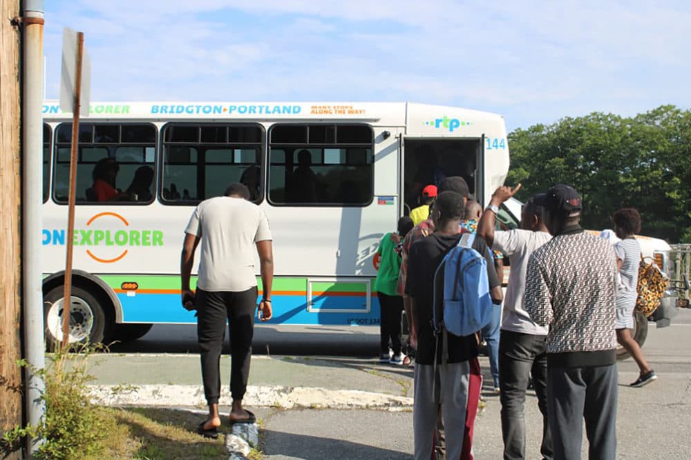 A group of asylum seekers, primarily from Angola and the Democratic Republic of the Congo, wait to board a bus on the side of Route 1 in Yarmouth. The new bus route connects the families to Portland, where they can access social services, African grocery stores, and medical facilities. (Ari Snider)