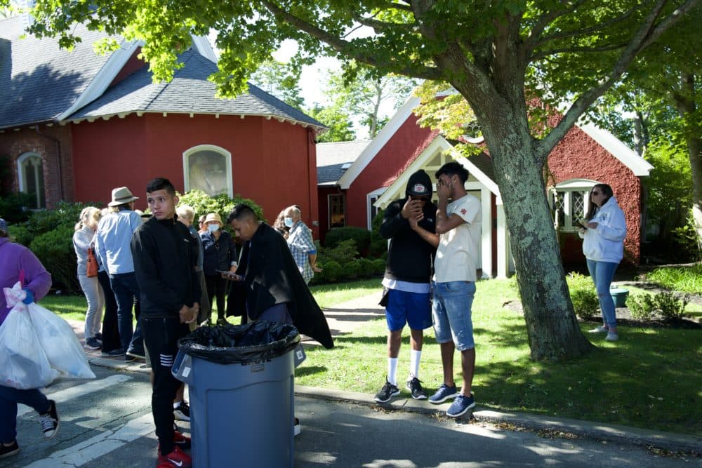 Several migrants flown from Texas to Martha's Vineyard stand outside St. Andrew's Church in Edgartown. (Sam Fleming for WBUR)