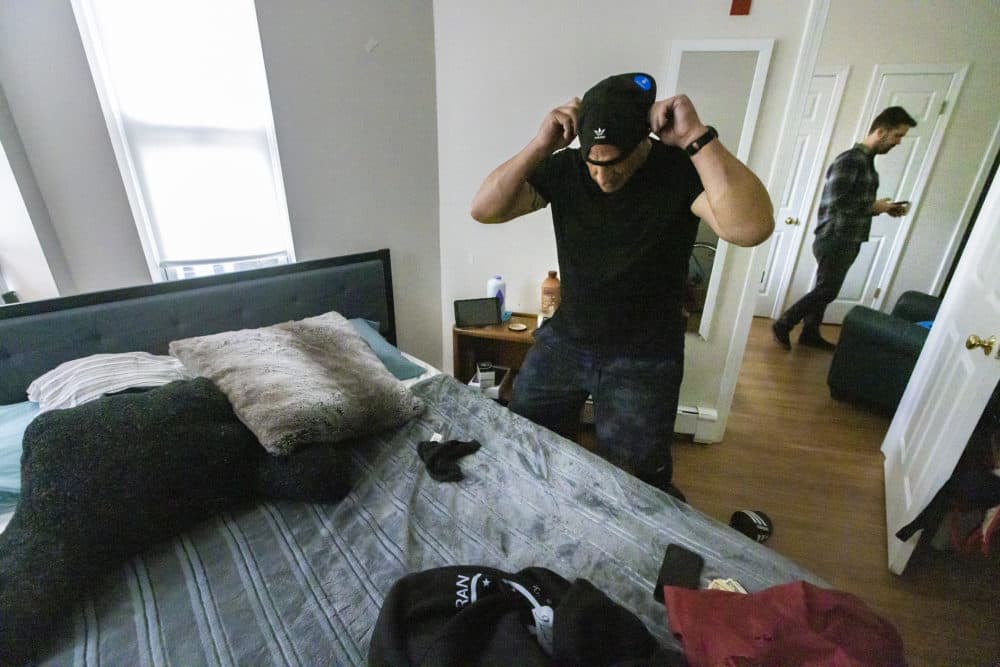 Mike Spinelli in his apartment in Boston's Fenway neighborhood. His housing case manager, Mark Bradshaw, is in the background. (Jesse Costa/WBUR)