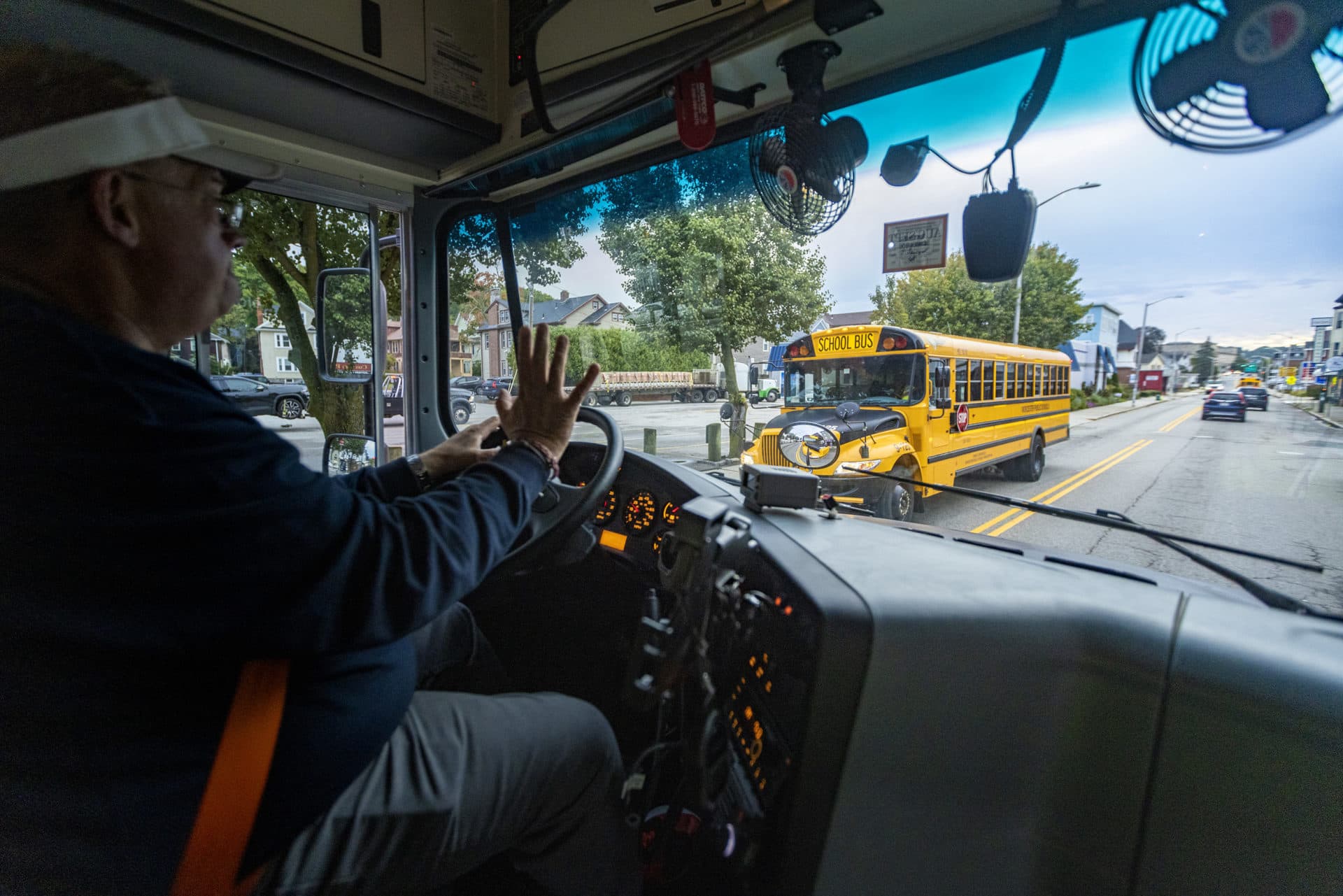 Bus driver Jason Crue waves as another Worcester school bus passes as he drives students to Worcester Technical High School. (Jesse Costa/WBUR)