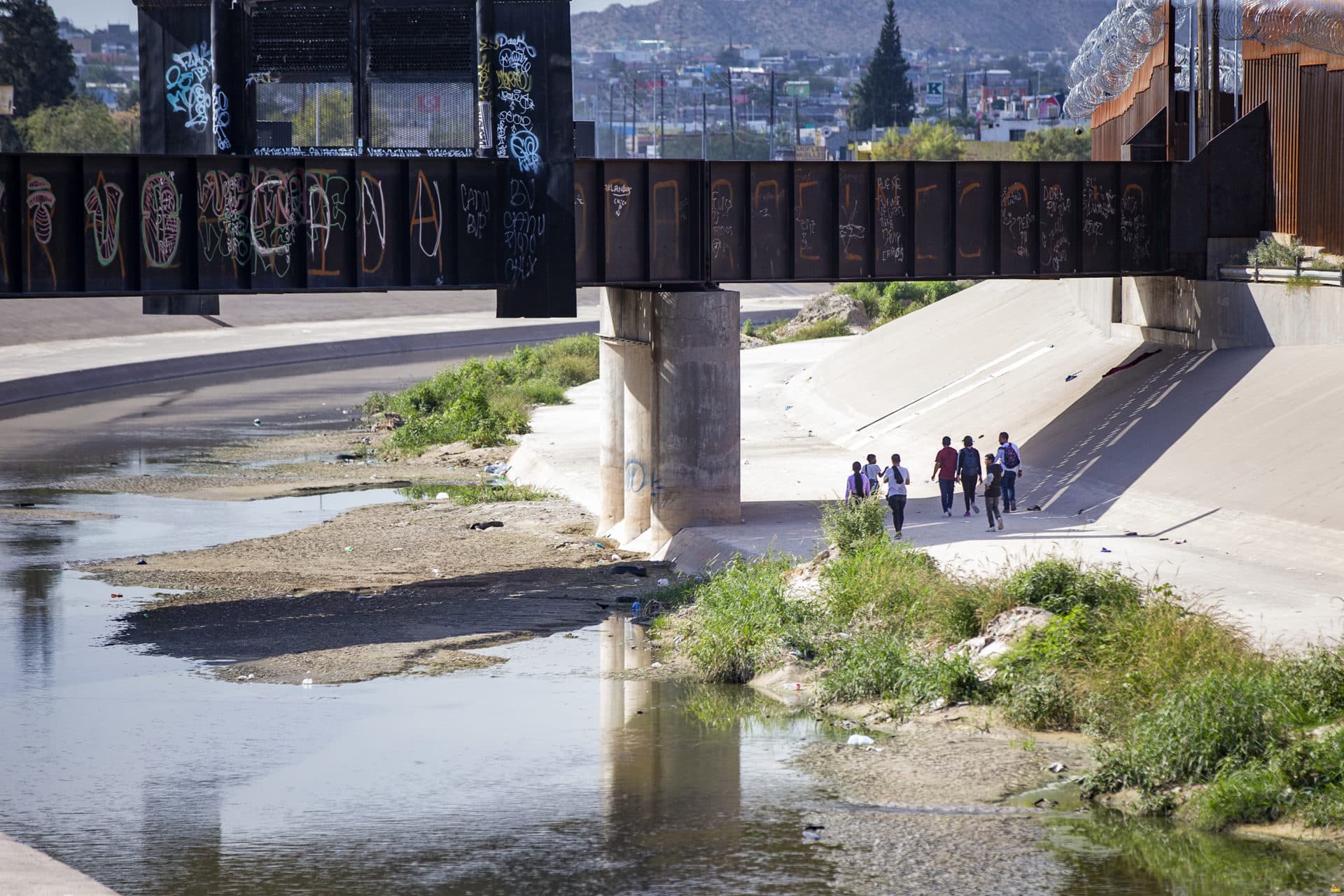 Immigrants walk along the U.S. side of the border in El Paso. (Jesse Costa/WBUR)