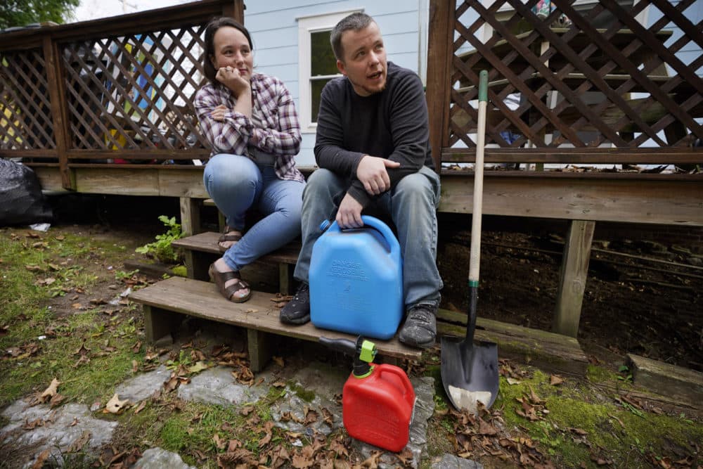Lucinda Tyler and Aaron Raymo sit outside their home with fuel containers they used to fill their heating oil tank at their home, Oct. 5, 2022 in Jay, Maine. (Robert F. Bukaty/AP)